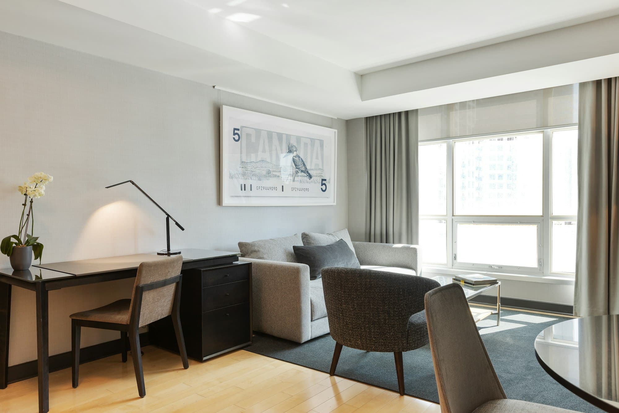 Business hotel room with a work desk, armchairs and floor-to-ceiling windows
